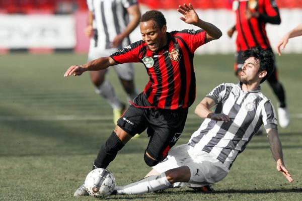A Budapest Honved FC player tries to keep possession of the ball against an Ujpest FC's player's attempt at a side tackle.