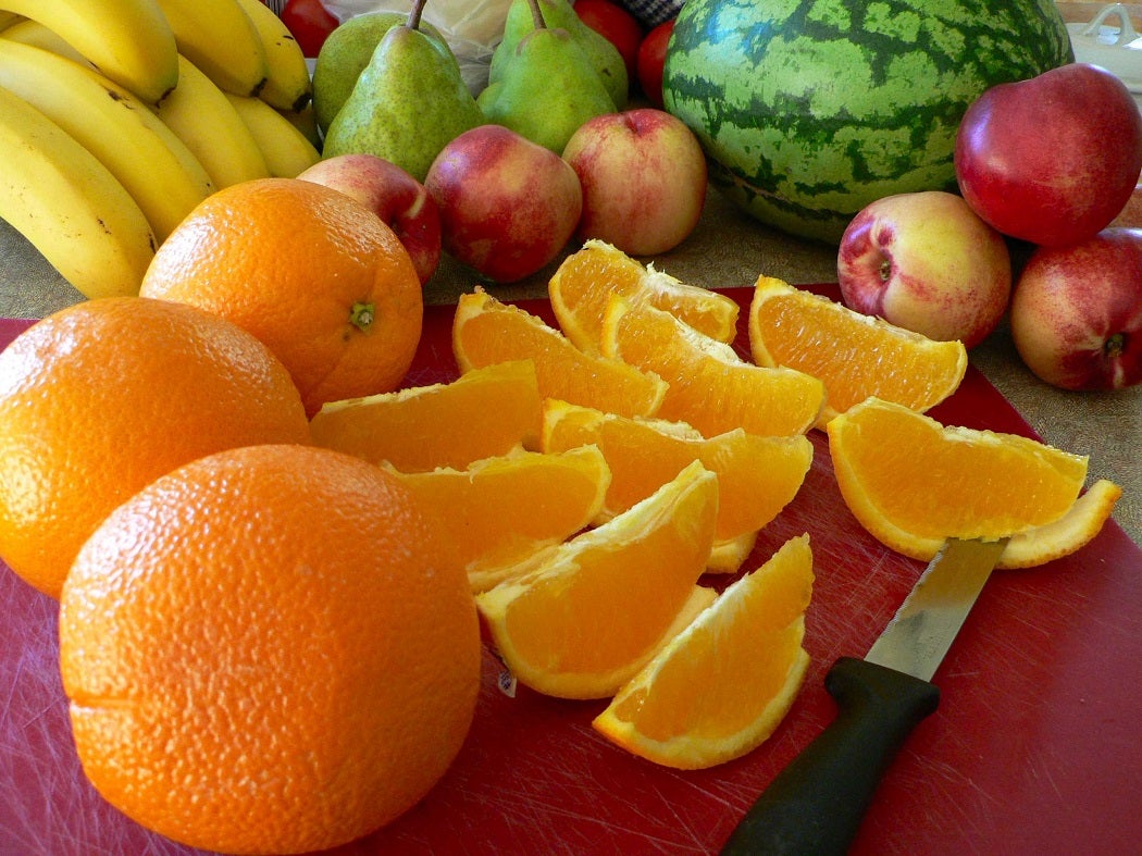 Various fruit with a sectioned orange in the foreground
