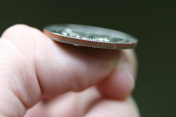 Close-up of a quarter balanced on a thumb just before a coin flip