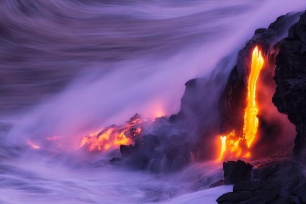Lava flowing into water while steam rises into the fog