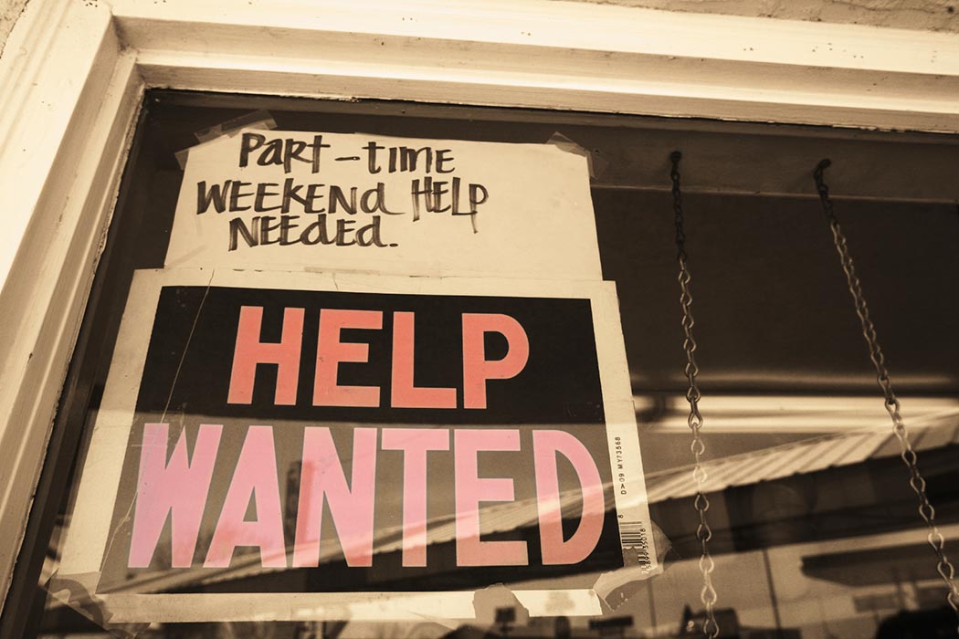 A Help Wanted sign hanging in a store window