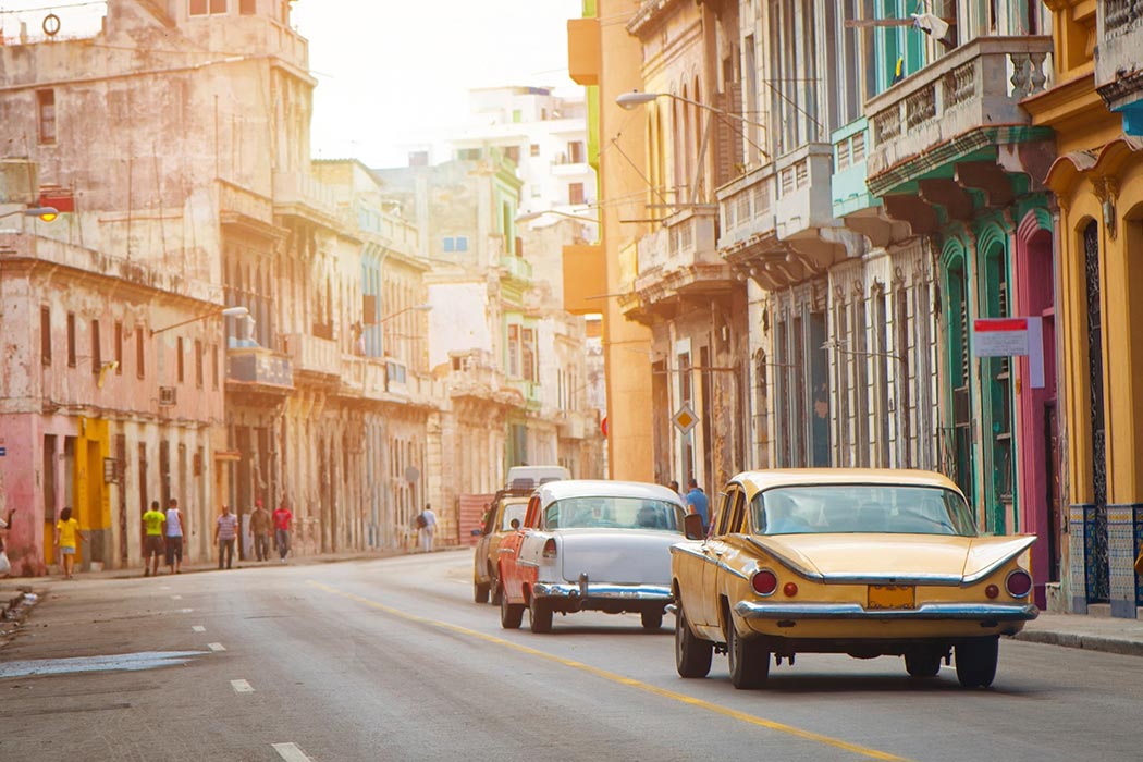 A modern street in Cuba with vintage cars on the road