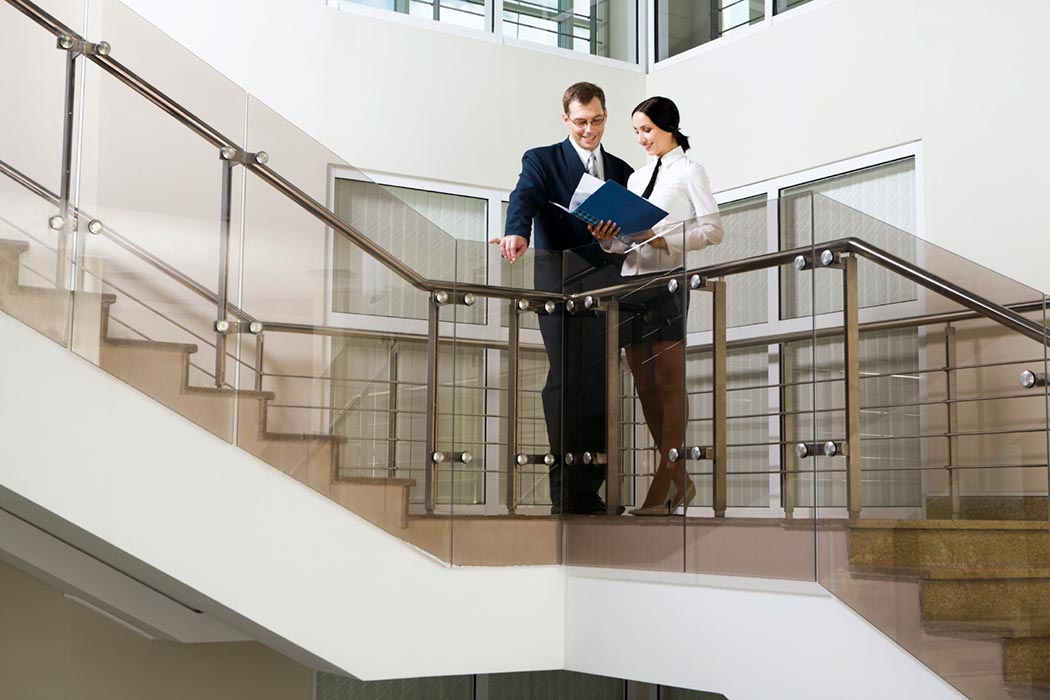 A man and woman look over a work report on a staircase