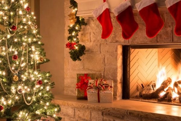 Stockings hung above a fireplace next to a Christmas tree and presents
