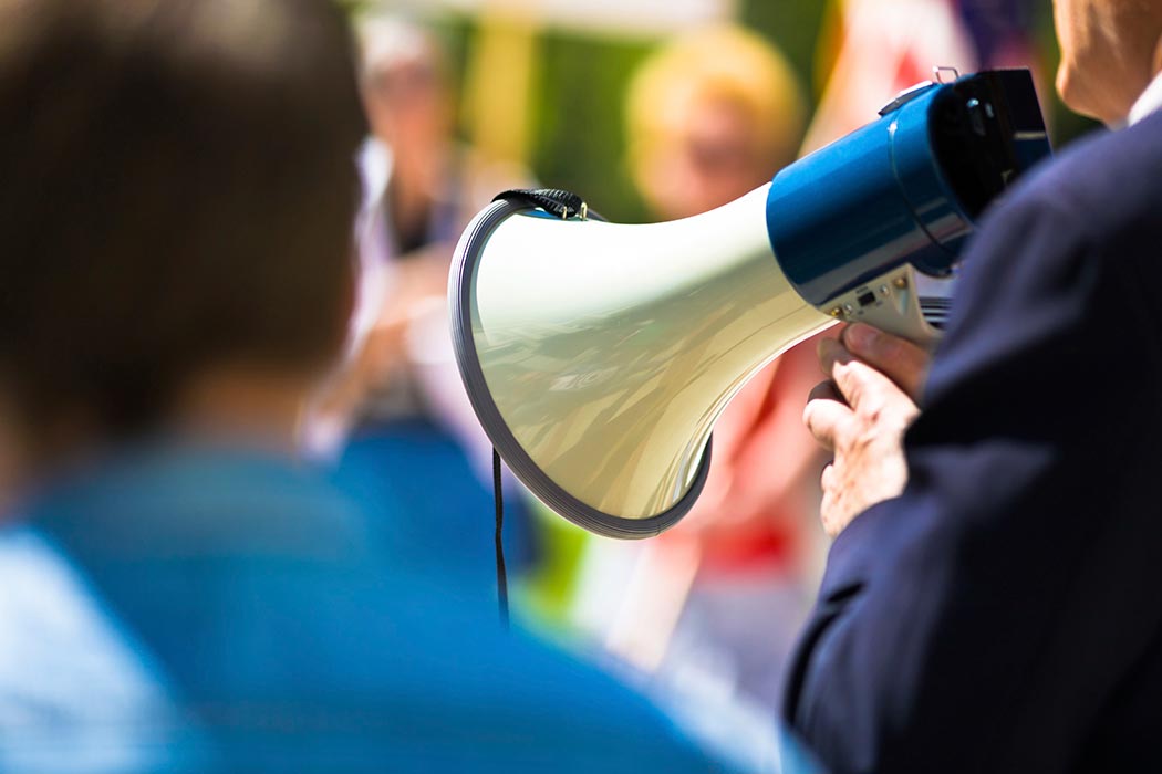 A leader speaks into a megaphone to a crowd.