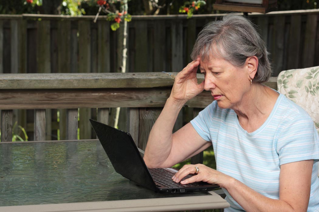 Worried senior woman using laptop.