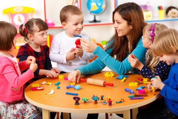 A daycare teacher plays with a group of children