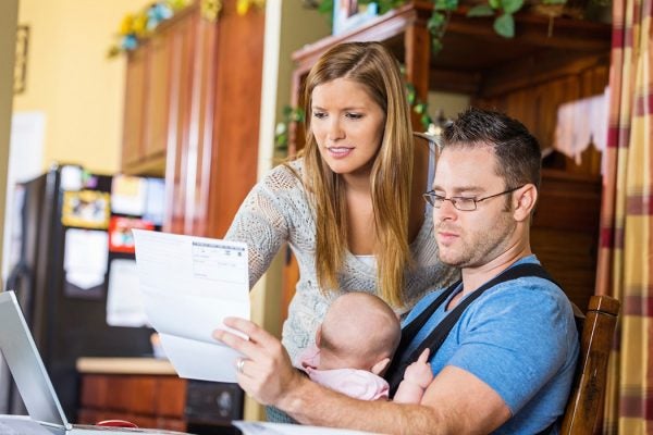 A couple with a baby look over their bills