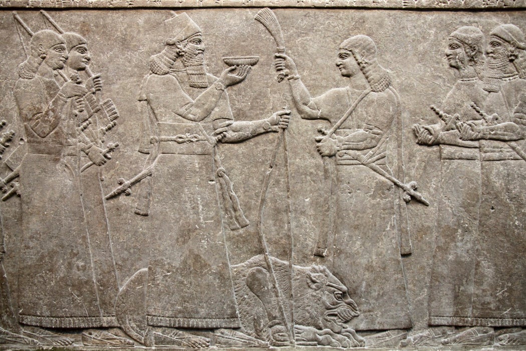 Ancient Assyrian relief 865-860 BC from Nimrud showing King Ashurnasirpal accompanied by his courtiers pouring a libation over a dead lion
