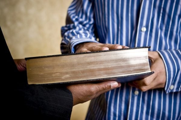 An individual puts their hand on the Bible