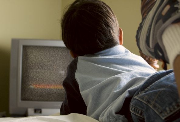 Boy watchng tv from the bed.