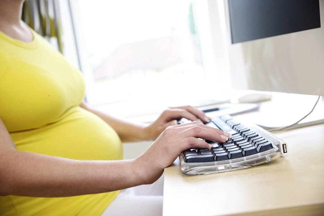 Pregnant woman typing on a keyboard