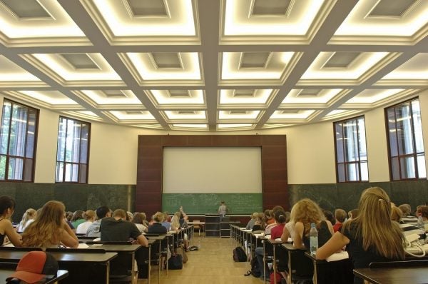 A large classroom with students all faced towards the chalkboard at the front of the room.