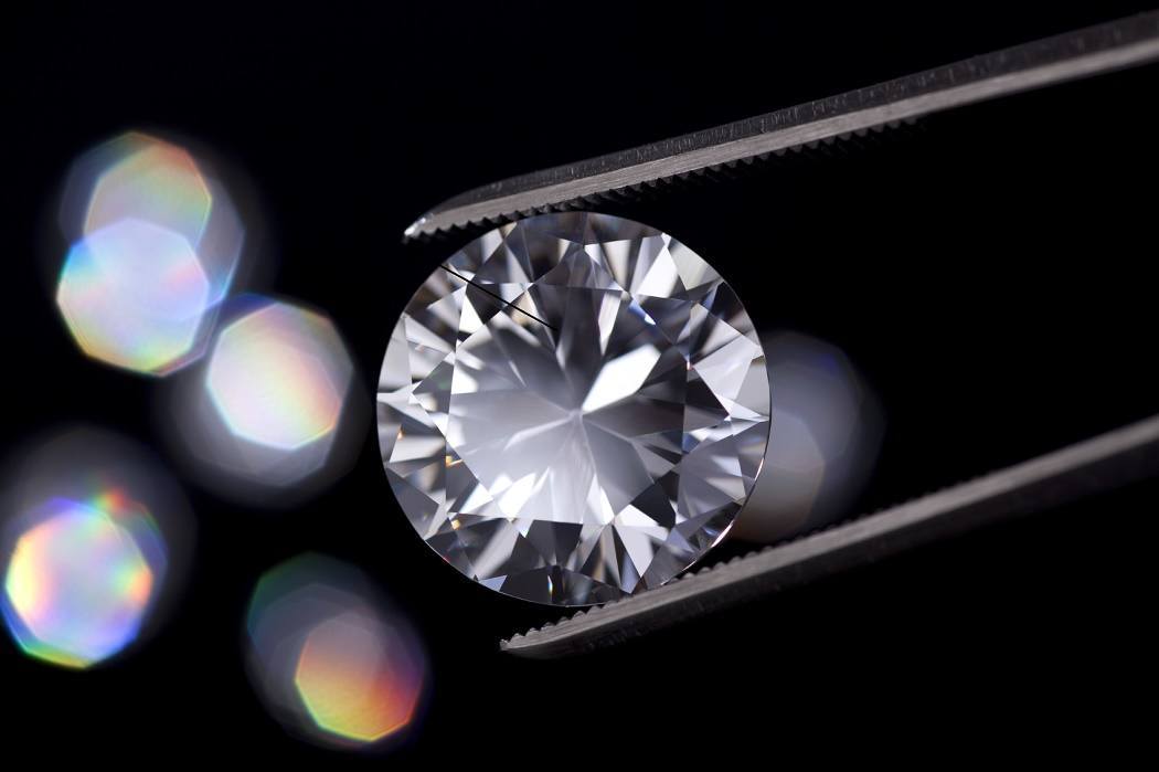 Close-up of a diamond held by jeweler's tweezers