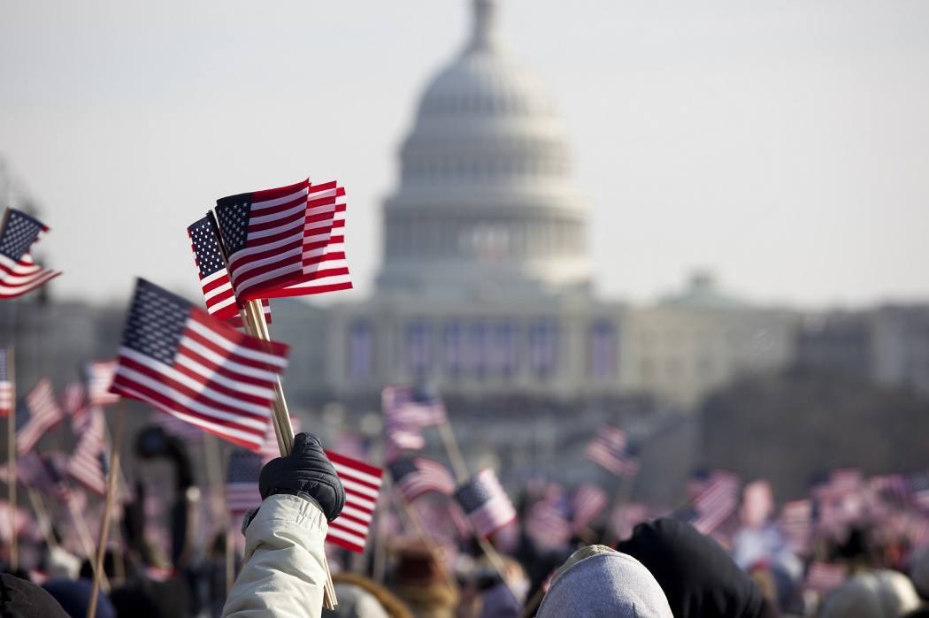 A crowd holding up American flags in front of the U.S. Capitol Building