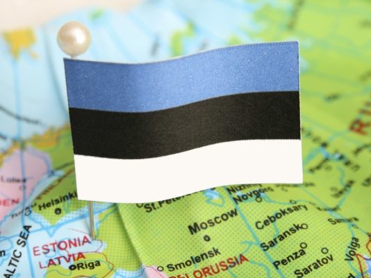 Estonian flag pinned into a globe showing the location of Estonia
