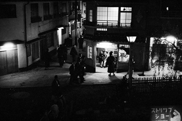 circa 1955: Women loiter in the doorways of nightclubs in Yoshiwara, the red light district of Tokyo, while prospective clients wander past or stop to look. (Photo by Orlando /Three Lions/Getty Images)