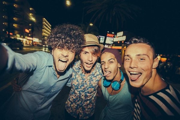 Four young men in trendy clothes take a selfie while out partying