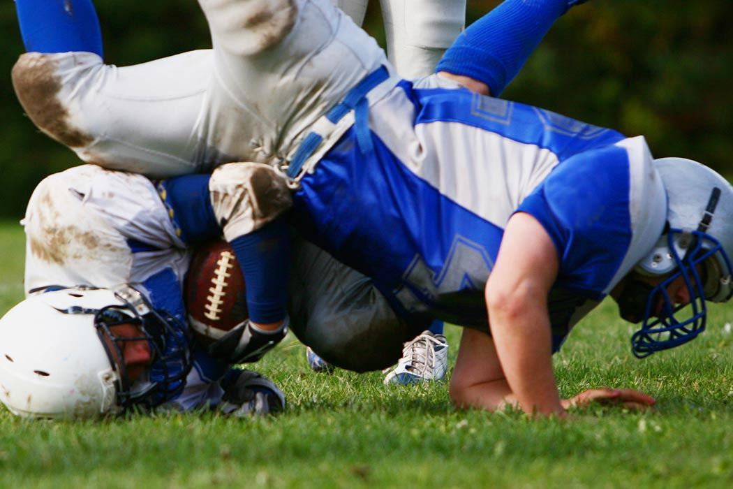 A football player holds onto the ball through a tackle