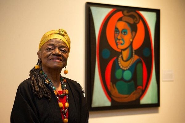 Artist Faith Ringgold poses for a portrait in front of a painted self-portrait during a press preview of her exhibition, "American People, Black Light: Faith Ringgold’s Paintings of the 1960s" at the National Museum of Women in the Arts in Washington on Wednesday, June 19, 2013. Ringgold explains her "confrontational art" _ vivid paintings whose themes of race, gender, class and civil rights were so intense that for years, no one would buy them. "I didn’t want people to be able to look, and look away, because a lot of people do that with art," Ringgold said. "I want them to look and see. I want to grab their eyes and hold them, because this is America." (AP Photo/Jacquelyn Martin)