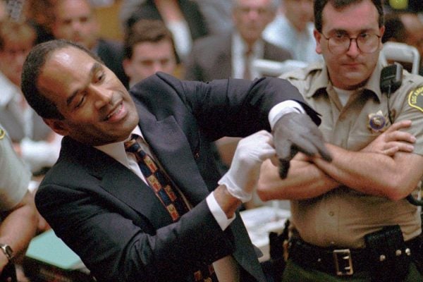 In this June 15, 1995, file photo, murder defendant, O.J. Simpson grimaces as he tries on one of the leather gloves prosecutors say he wore the night his ex-wife Nicole Brown Simpson and Ron Goldman were murdered, during the Simpson double-murder trial in Los Angeles. A lawyer for O.J. Simpson in Las Vegas says the imprisoned former football star isn’t happy with portrayals he’s seen in ads and interviews about a cable TV series focusing on his 1995 murder acquittal in Los Angeles. Simpson won’t be able to see the show, "The People v. O.J. Simpson," as Nevada prisons don’t carry the FX network, which debuts the 10-part show on Tuesday, Feb. 2, 2016. (Sam Mircovich via AP, Pool, File)