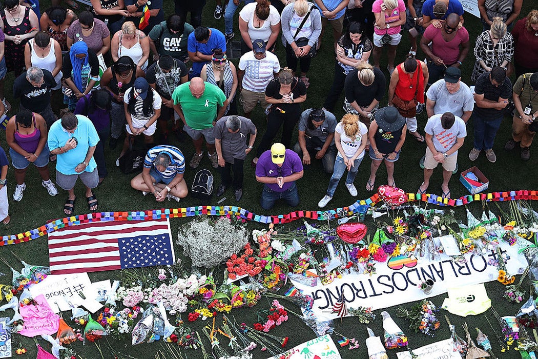 People pray together during a memorial service on the grounds in front of the Dr. Phillips Center for the Performing Arts for the victims of the Pulse gay nightclub shooting