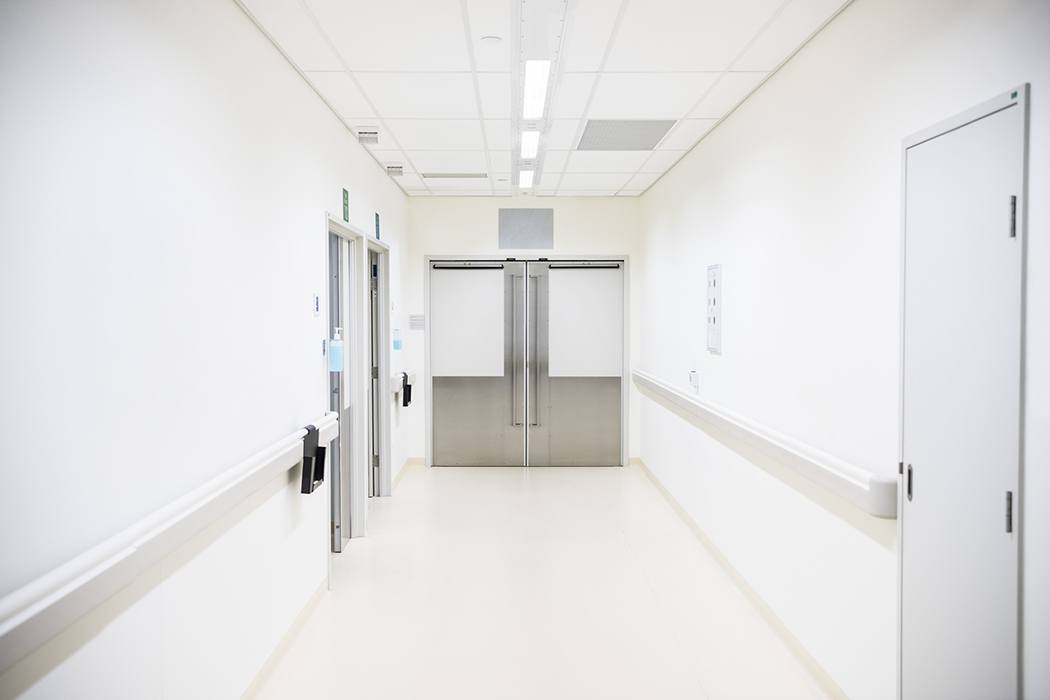 Empty hospital corridor with closed doors at the end