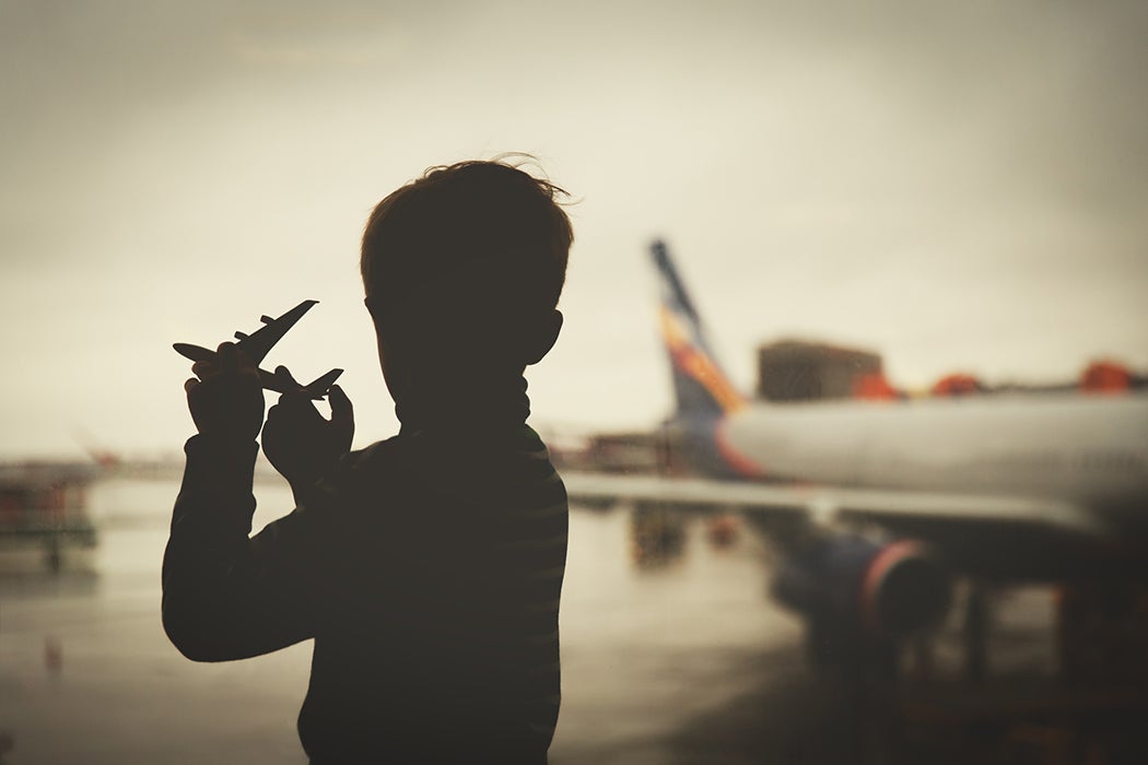 boy playing with toy plane while waiting in airport