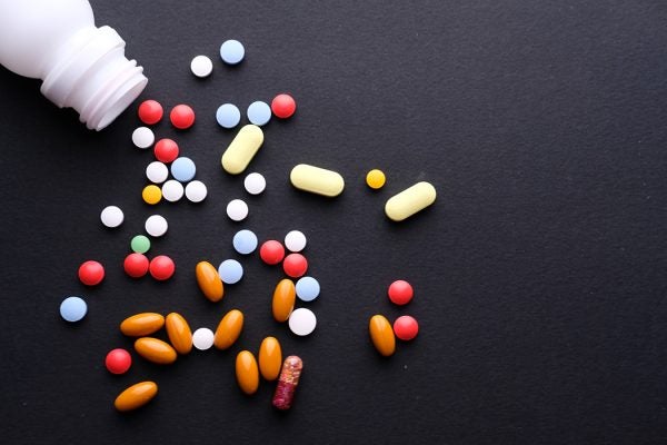Many pills and tablets with bottle isolated on black background.