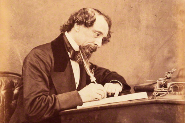 Charles Dickens in 1858 writing at a desk