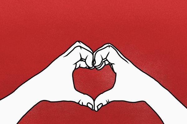Cropped hands of person making heart shape against red background