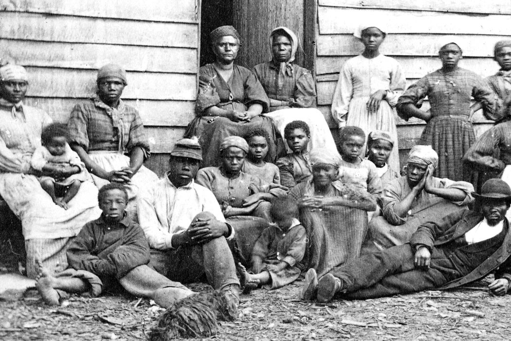 A group of slaves gathered outside a building at the Foller Plantation in Cumberland Landing, Pamunkey Run, Virginia, May, 1862.