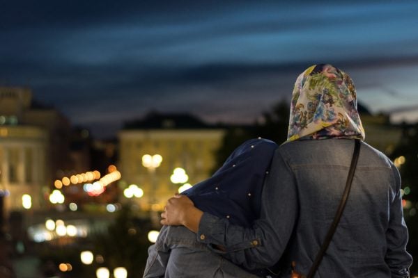 Two muslim women looking out over a city.