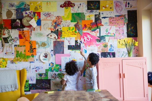 Two children looking at artwork hung on the wall