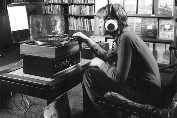 A teenager listening to a record through headphones