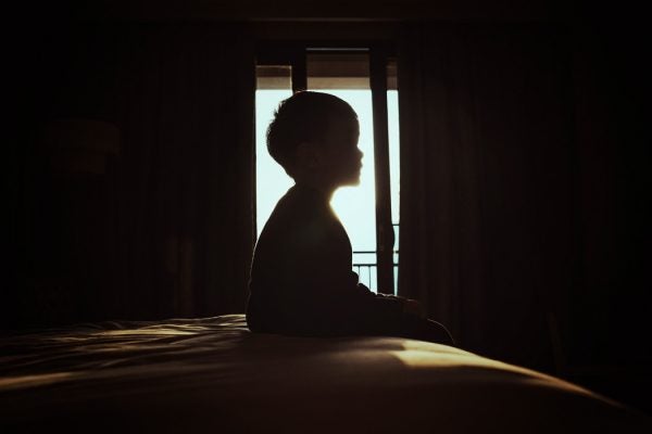 A child sitting in front of a window on a bed