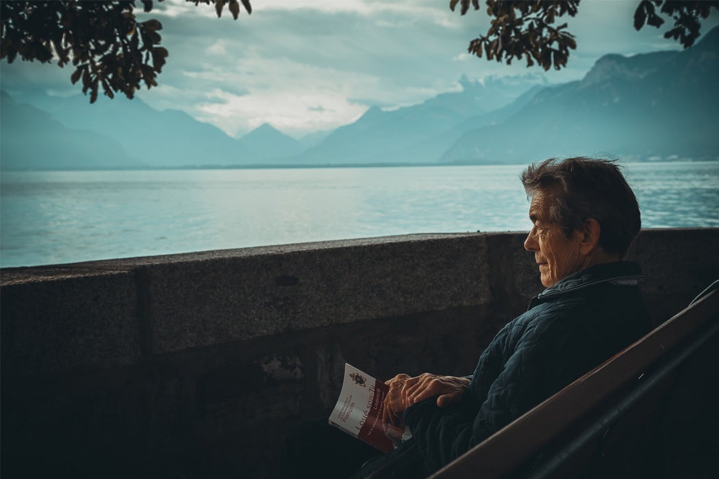 An elderly man sitting beside a lake