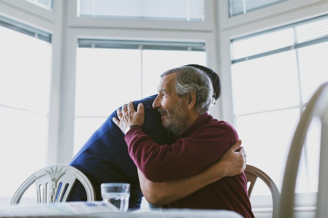 Caretaker embracing senior man at home