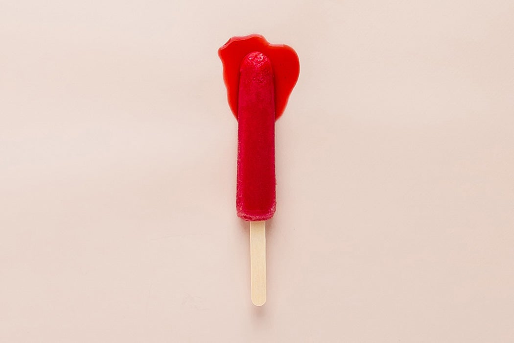 A red popsicle beginning to melt