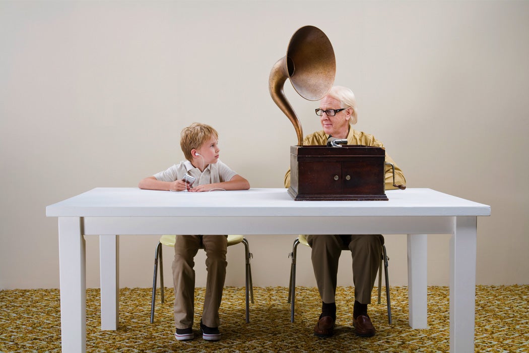 A child and old man sitting at a table with their respective music technologies