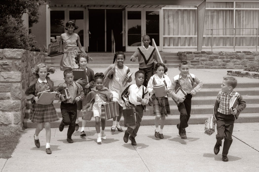 Circa 1960s: Group Of Grade School Children Running Down School Stairs With Books & Bags.