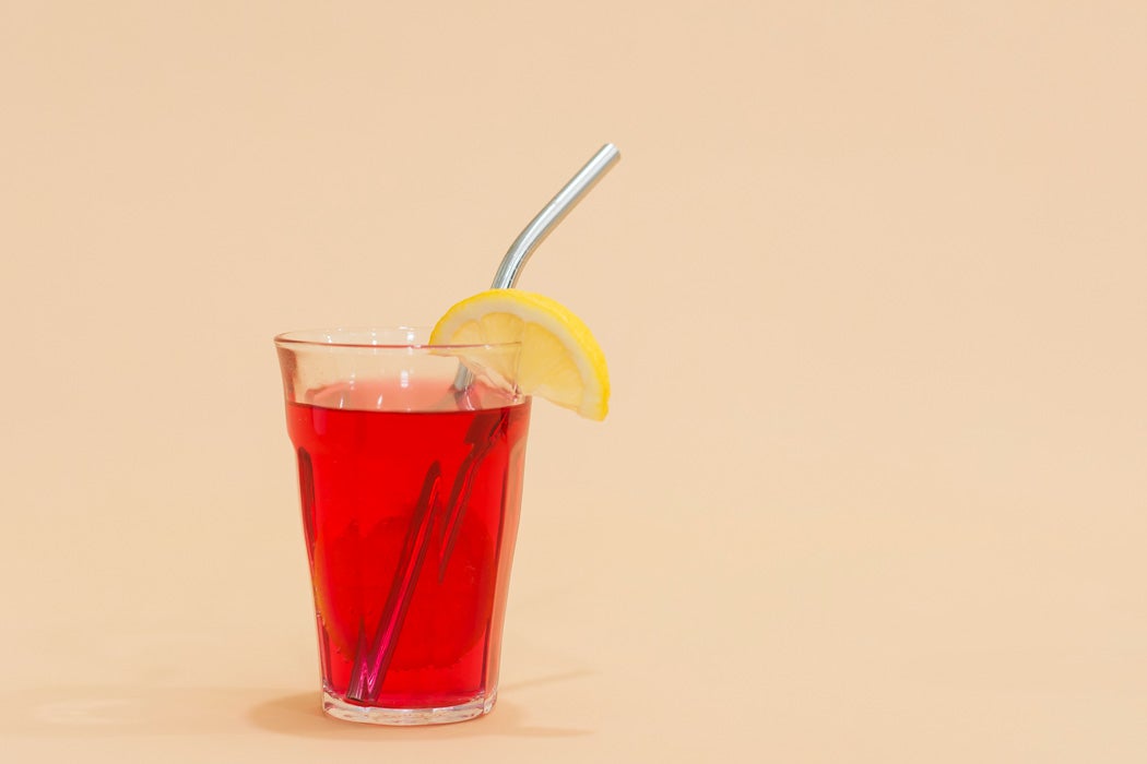A red drink in a glass with a metal straw