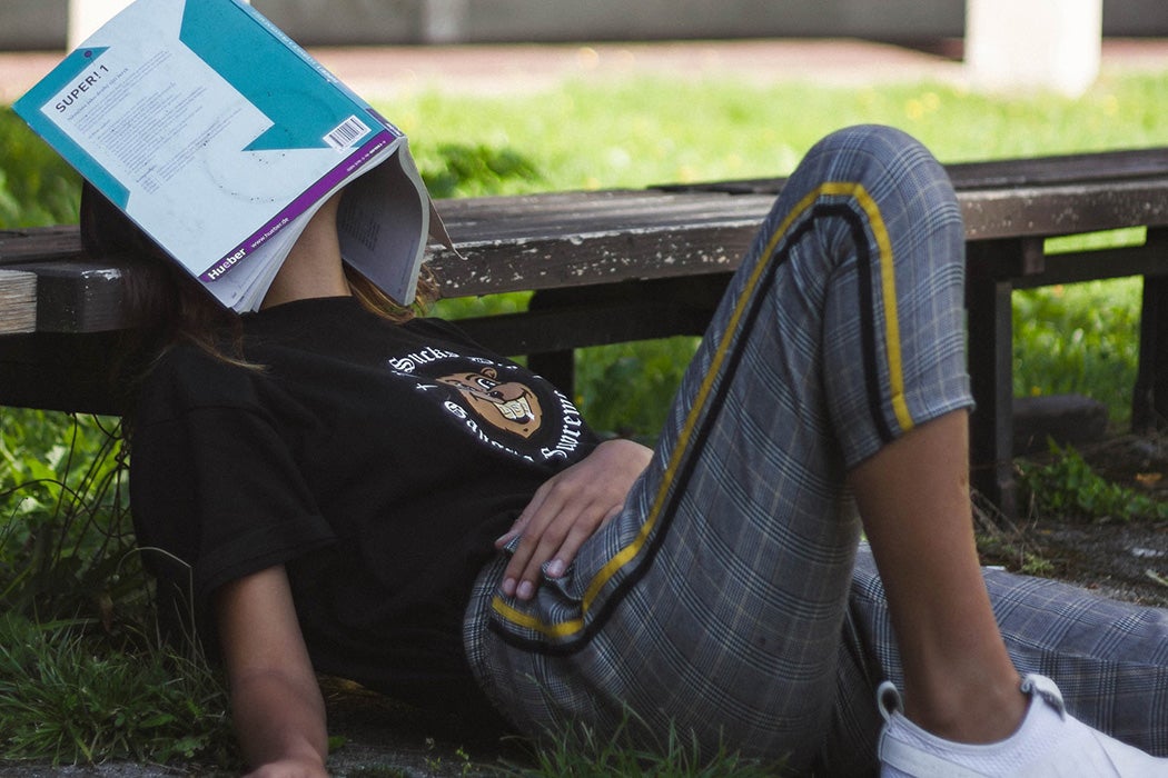 A person reclining with a book over their face