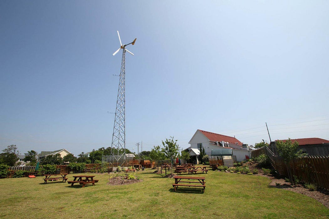 A tall wind turbine in the midst of a yard