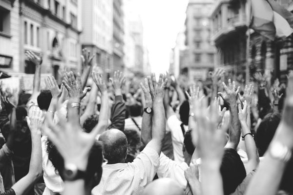 Peoples with hands raised gathered on street.