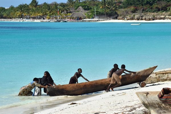 Children push a fishing boat to shore in Zanzibar