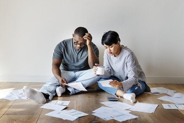 A couple sitting on the floor attempting to understand paperwork