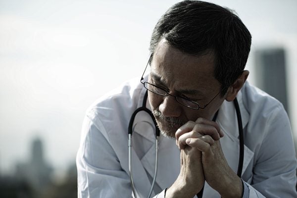 A male doctor sitting down and looking pensive