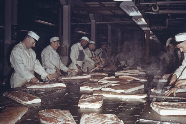 Men prepare bacon at a meat packing plant in Chicago, circa 1955