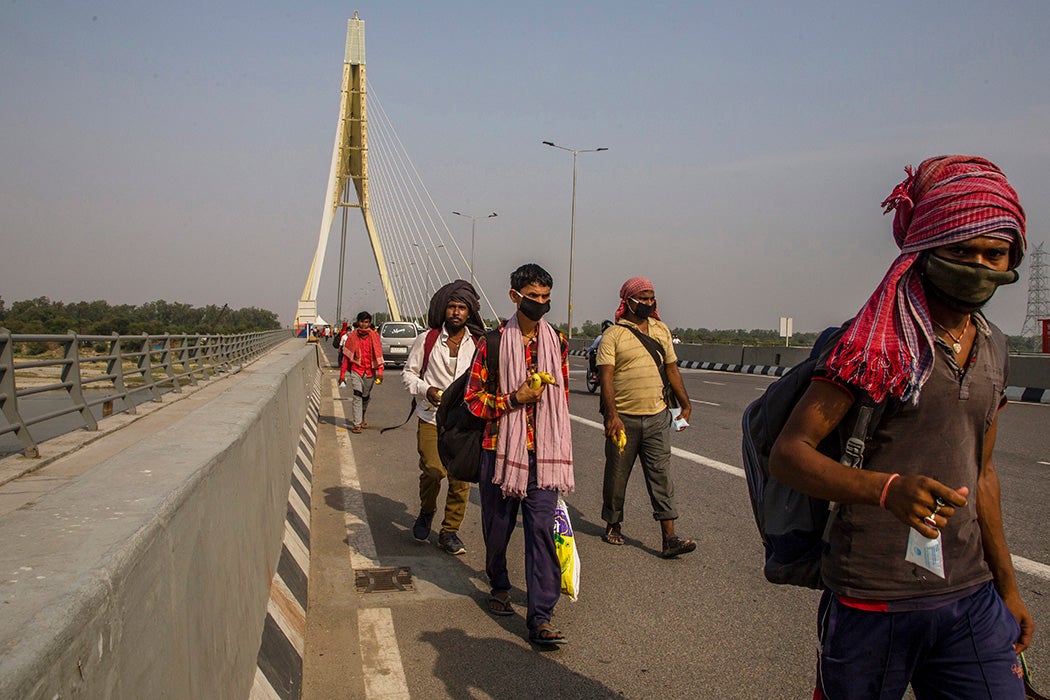 Indian migrant workers walk on a bridge after they were stopped by police while returning to their native places, as the country relaxed its lockdown restriction on May 14, 2020 in New Delhi, India